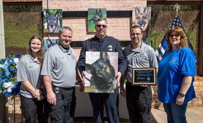 Schaffer at the WRTP K-9 memorial holding a photo of Faust.